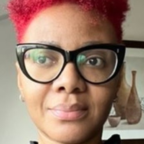 Woman with red hair and glasses near window.