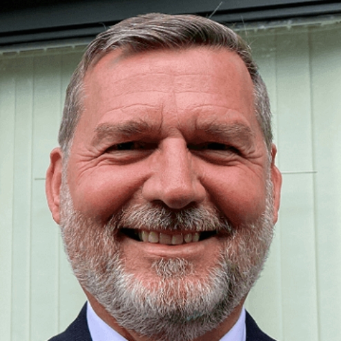 Smiling man standing outside a building entrance.