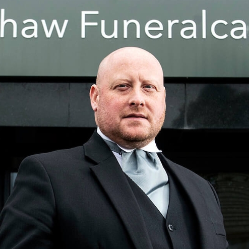 Man in suit standing outside Wishaw Funeralcare.