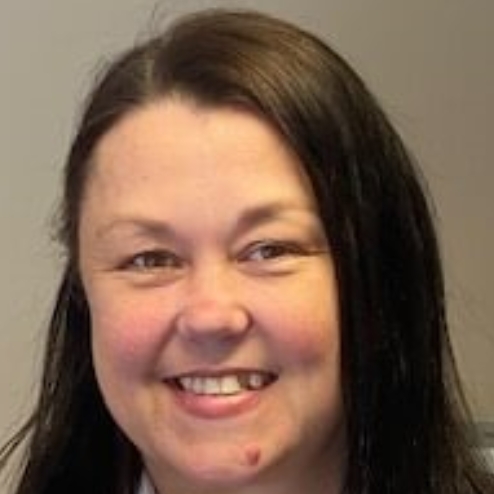 Smiling woman in office with photo collage behind her.