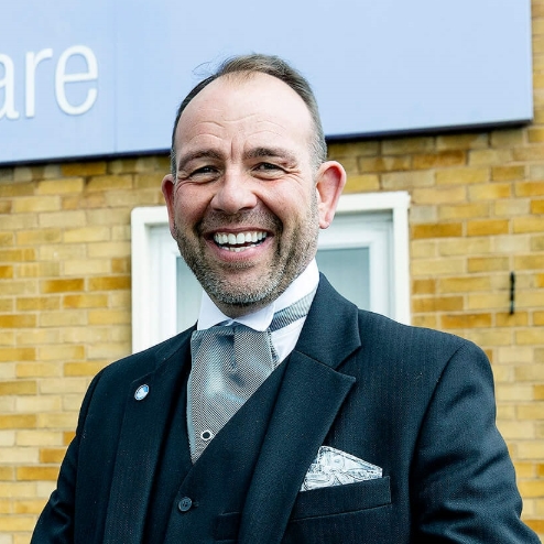 Smiling man outside Co-op Funeralcare building.