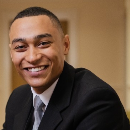 Smiling man in suit sitting in hallway.