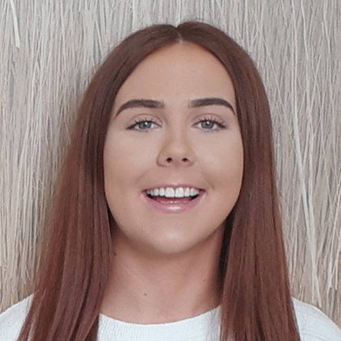 Smiling woman standing in front of textured wall.