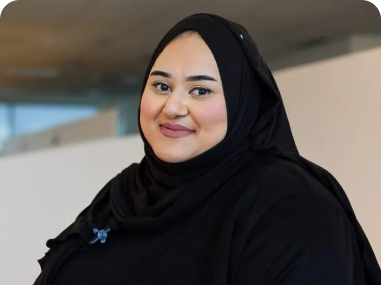 Individual in black clothing and hijab standing indoors