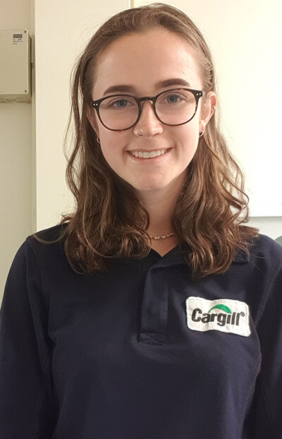 Cargill early careers professional wearing a branded navy polo shirt, photographed in an indoor office setting that reflects learning, growth, and early career development opportunities.