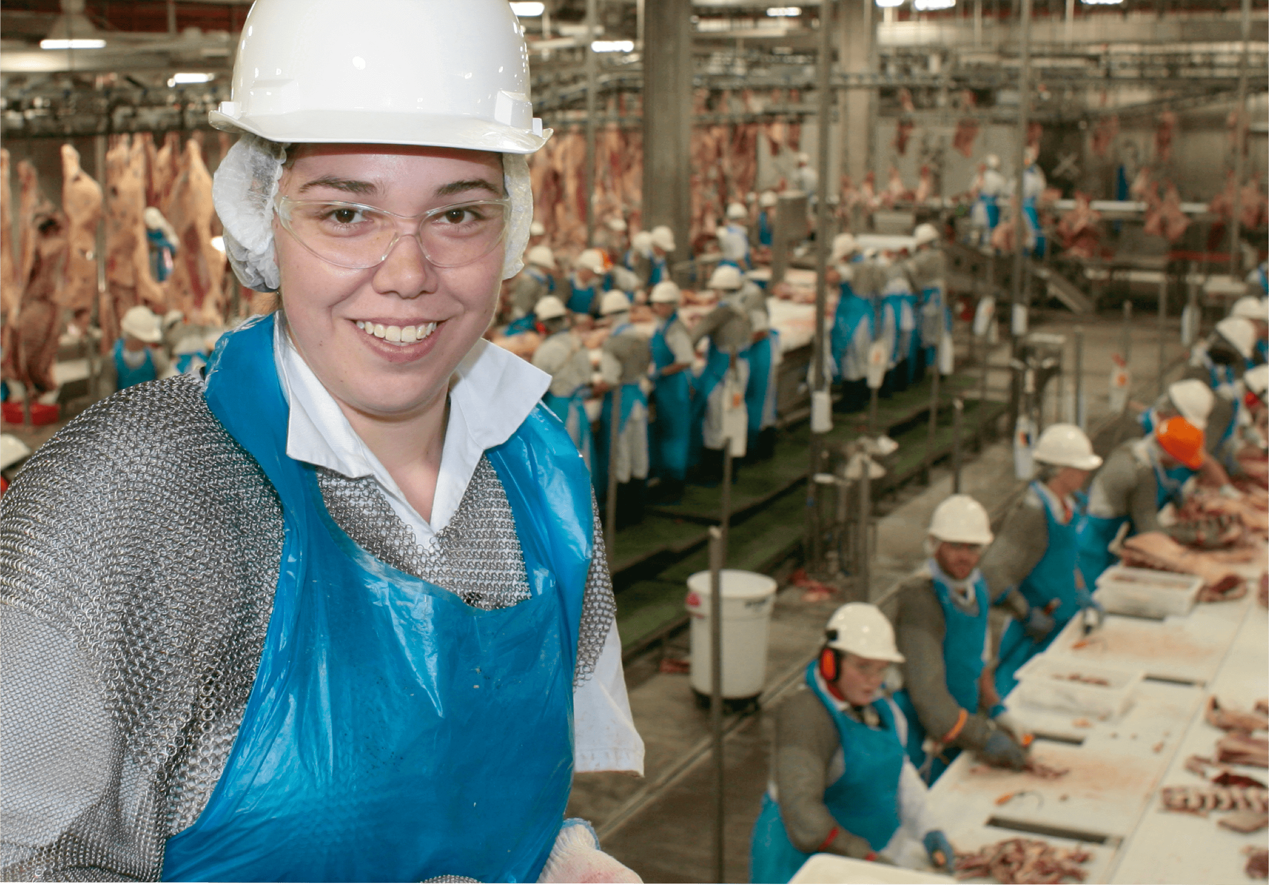 A woman in protective gear smiling in a food plant