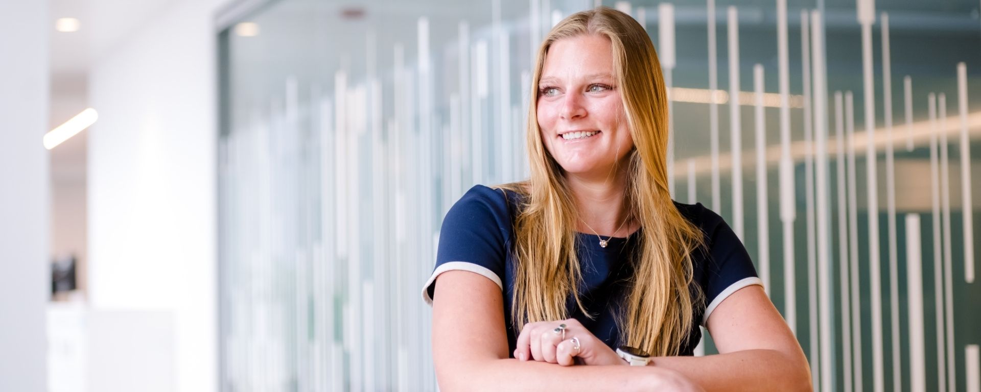 Capital One associate leans arms against the back of a yellow sofa chair and smiles while looking away
