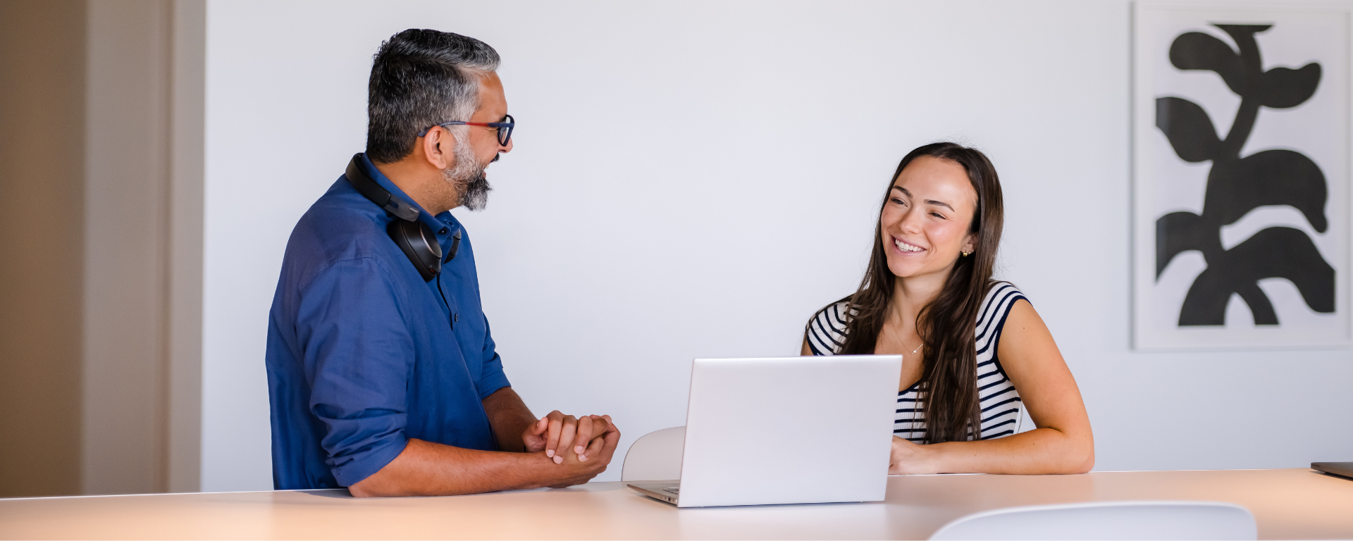 Two Capital One associates sitting at a table with a laptop and laughing