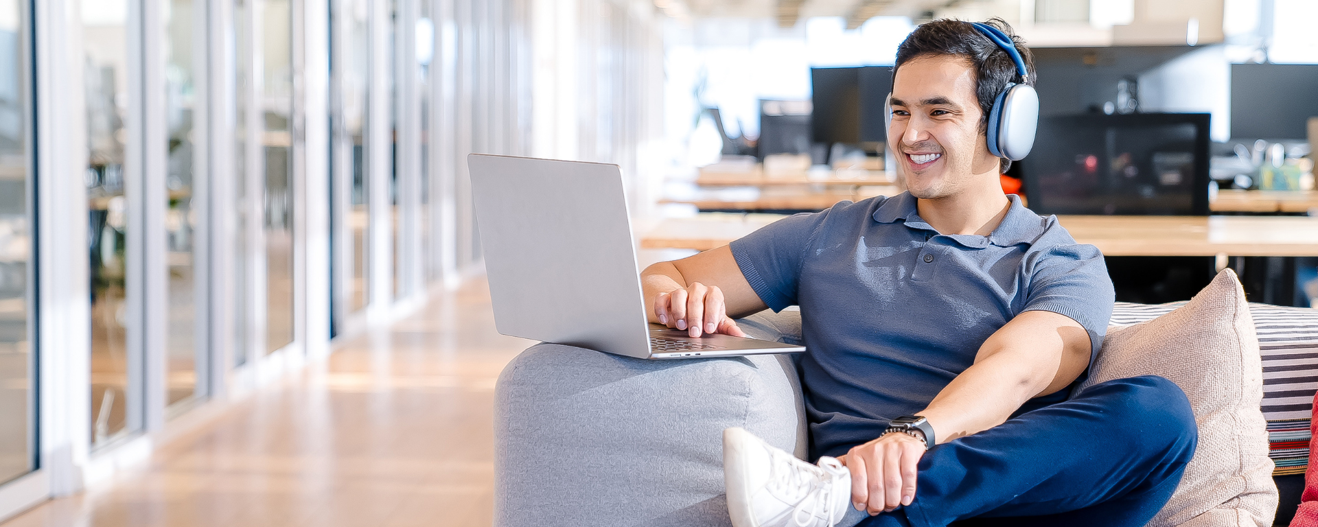 Capital One associate smiling on couch and working on laptop