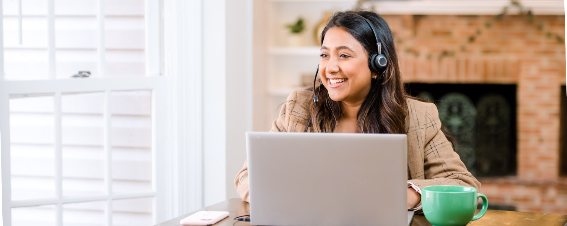 Capital One Customer Care associate sits at her laptop working and smiling, wearing a headset