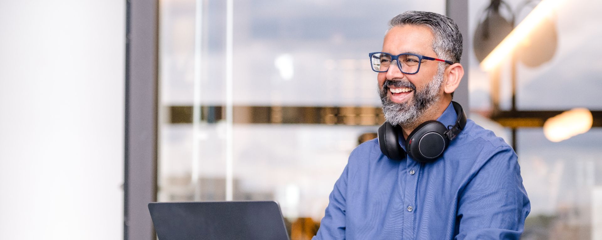 Capital One associate wearing a blue button down wears headphones around his neck