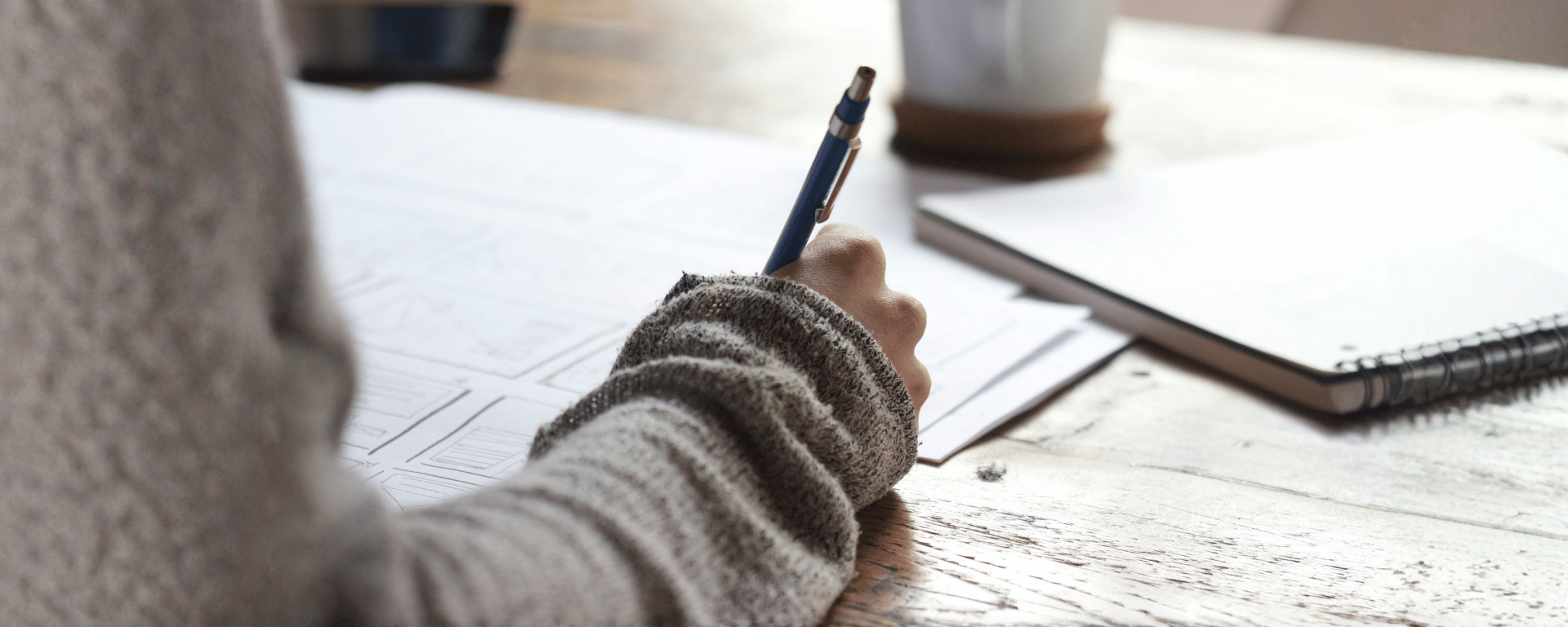 Person writing on a stack of papers with a pen