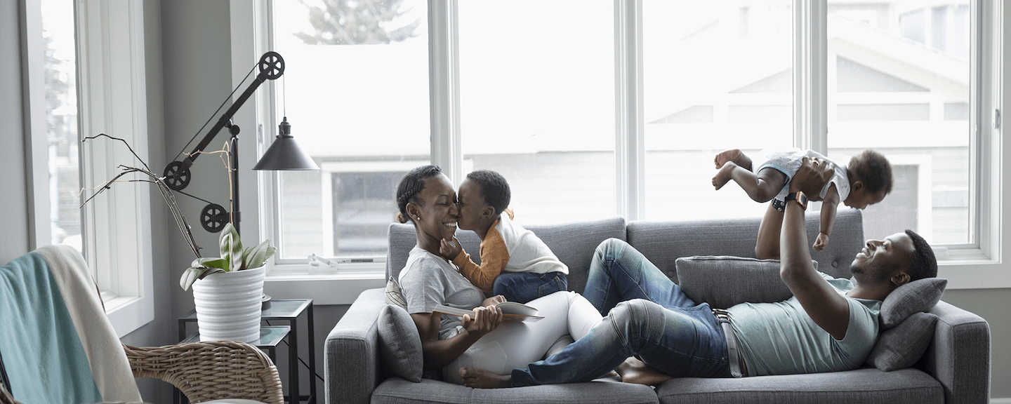 A Capital One associate sits on their couch with their spouse and 2 kids