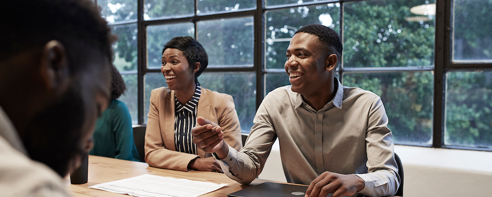 Two Capital One associates smile while discussing work in front of a glass window