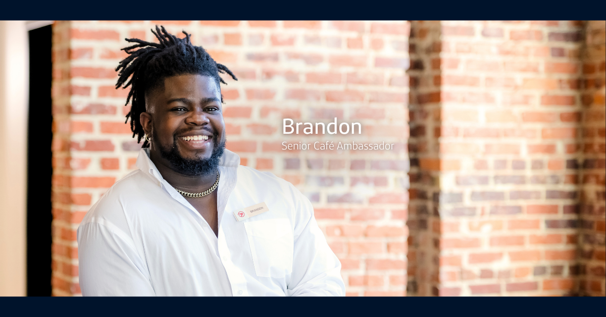 Capital One Senior Café ambassador Brandon wears a white button down shirt and smiles at the camera