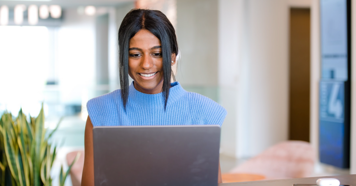 A Capital One associate wearing a blue top smiles at her laptop