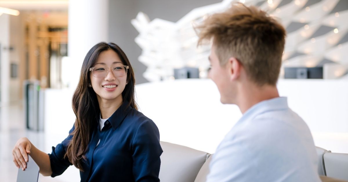 Capital One associates sit side by side in office talking