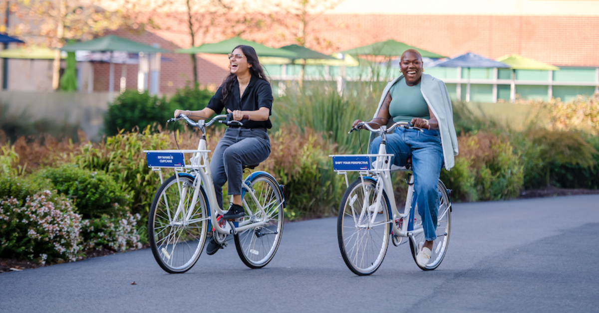 Two Capital One associates ride bikes around campus