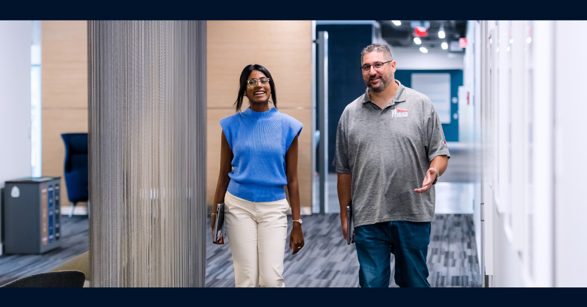 Two Capital One associates walk through a hallway, smiling and talking to each other