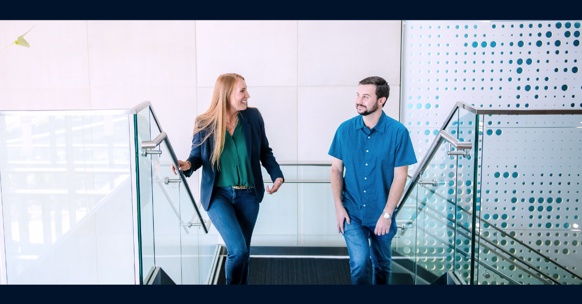 Two Capital One associates walk up a flight of stairs together, talking and laughing