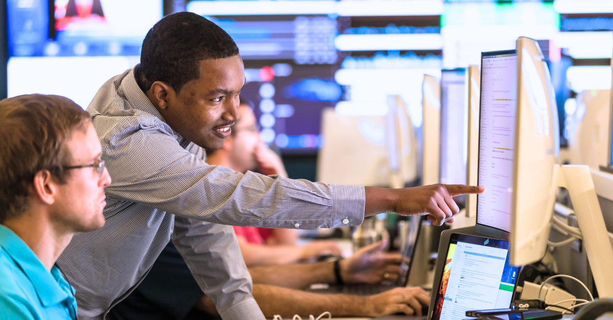 Two Capital One Tech associates work on a computer