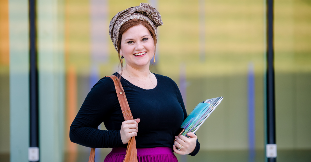 Capital One associate stands and smiles holding her laptop