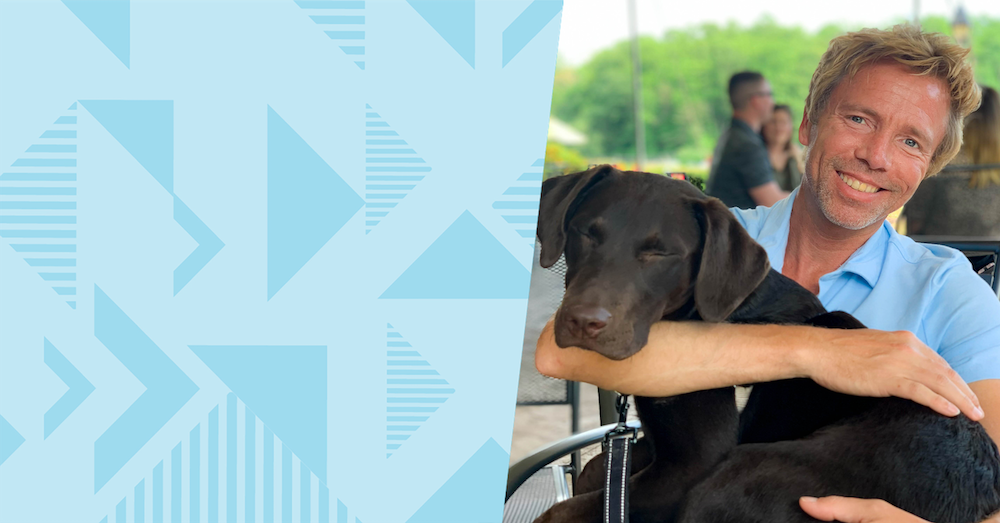 Jason P, Capital One associate, sits outside with his black lab in his lap