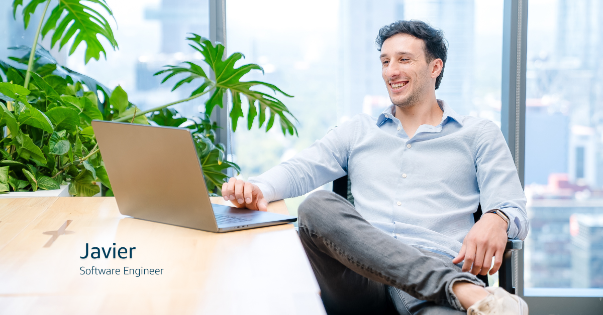 Capital One associate Javier working on a laptop and smiling