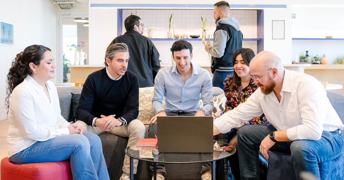 Group of Capital One associates gathered around a table with a laptop