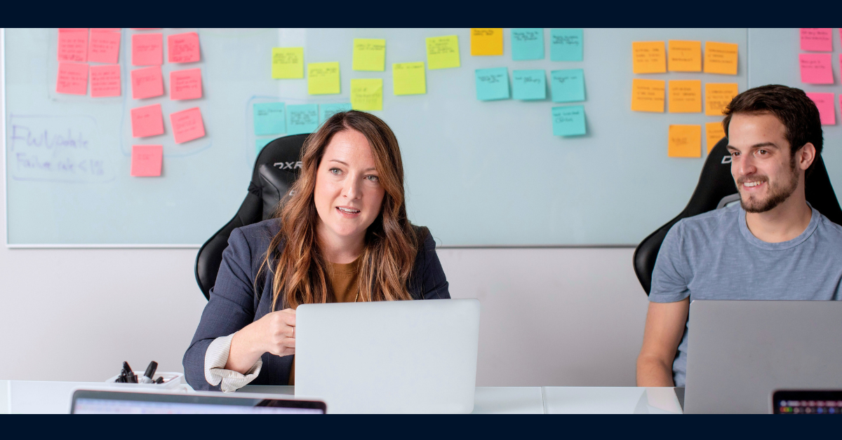 Two associates sitting in a meeting room with their laptops open