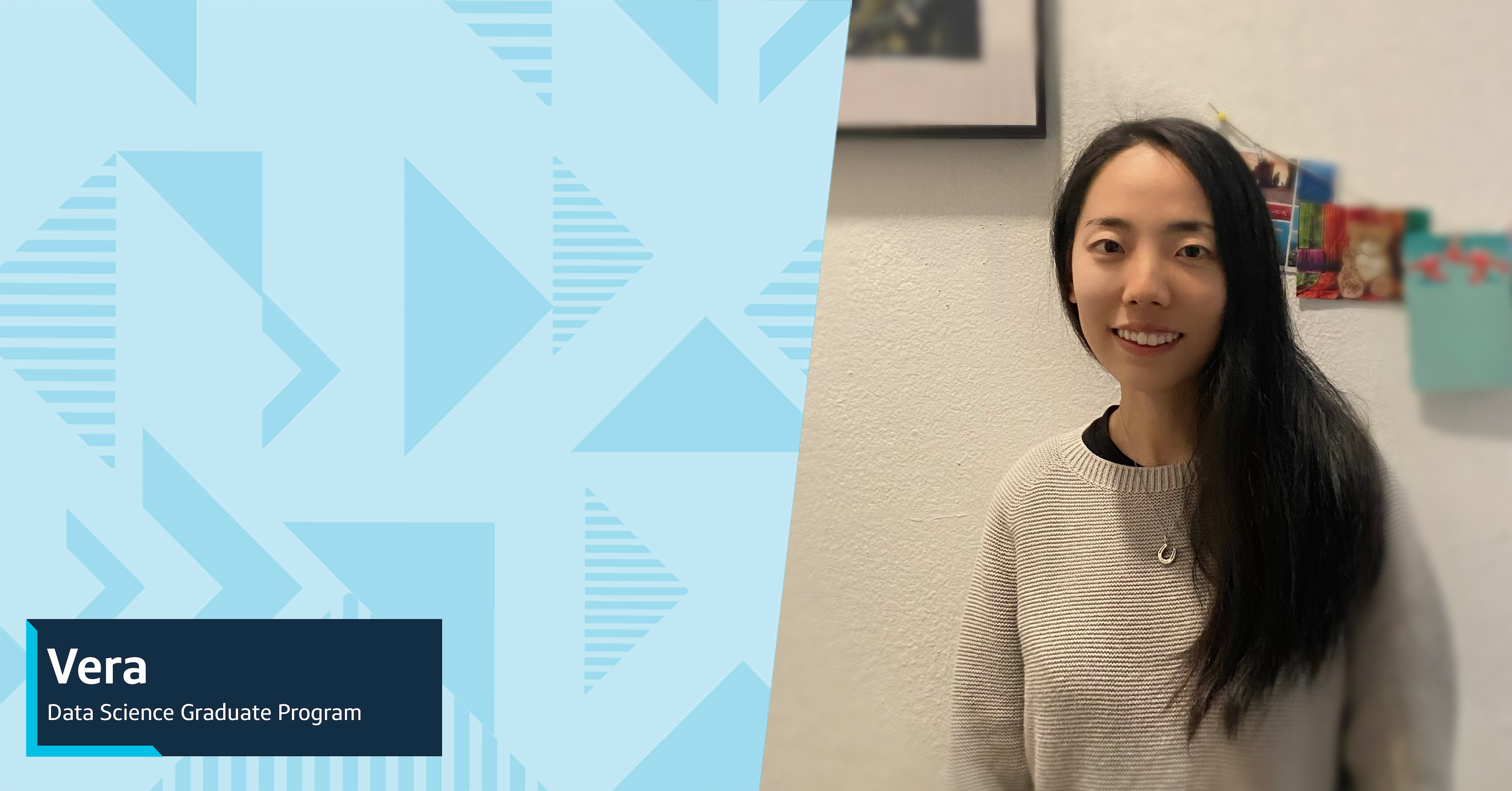 Vera, Capital One Data Science Graduate Program associate, stands in front of a white wall in front of hanging cards and smiles