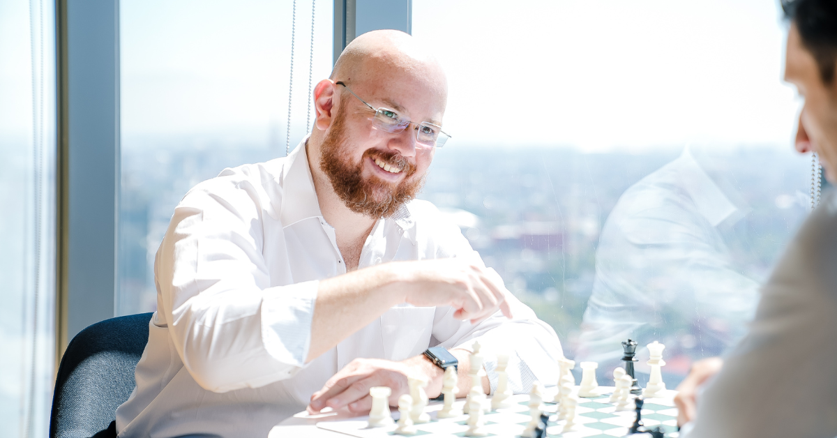 A Capital One associate sits in front of a window and plays chess