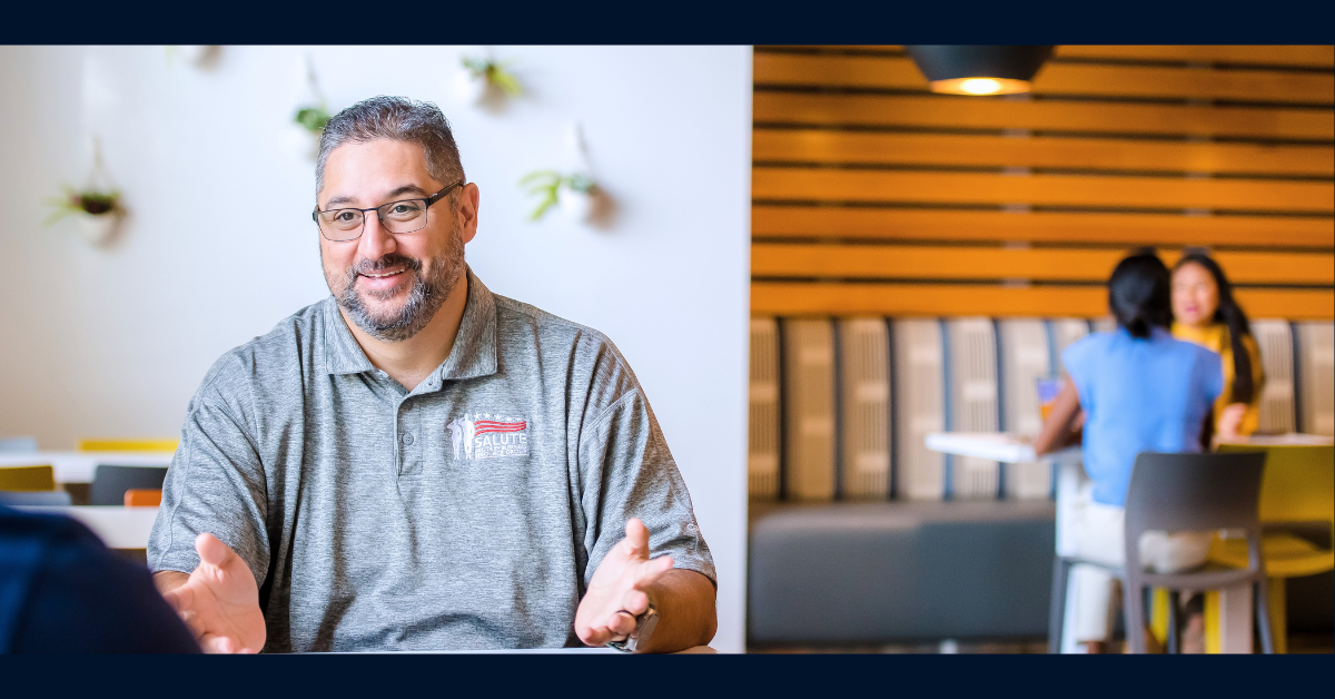 Capital One associate wearing a gray polo shirt and talking to a customer