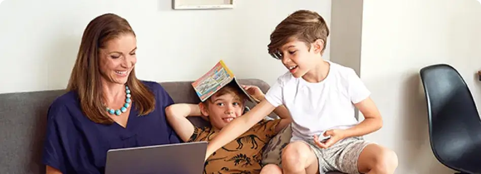 mother with her two children on a laptop while sitting all together on a couch smiling