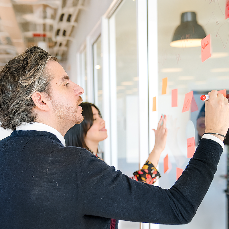 Three coworkers around one laptop at a conference table.