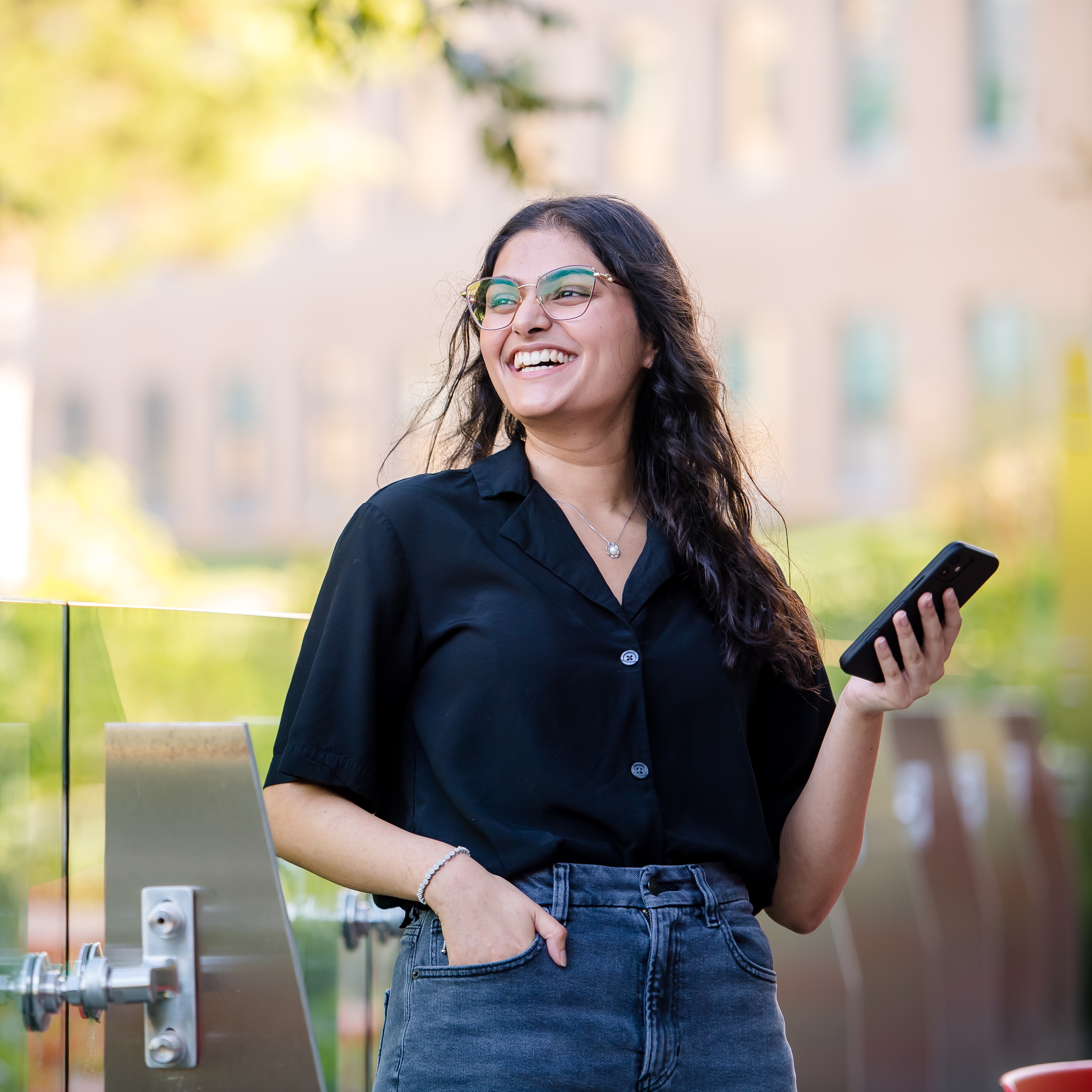 Capital One CODA associate stands outside holding her phone and smiling