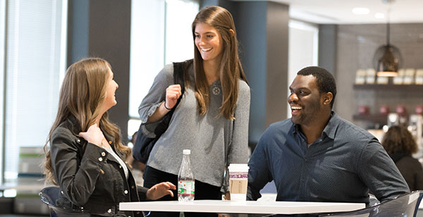 Three coworks in conversation at a cafeteria table