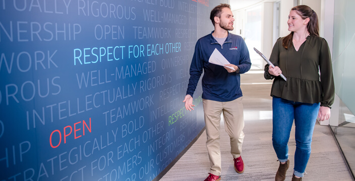 Two people walk down a hall that has a mural with the words 'Respect for each other'