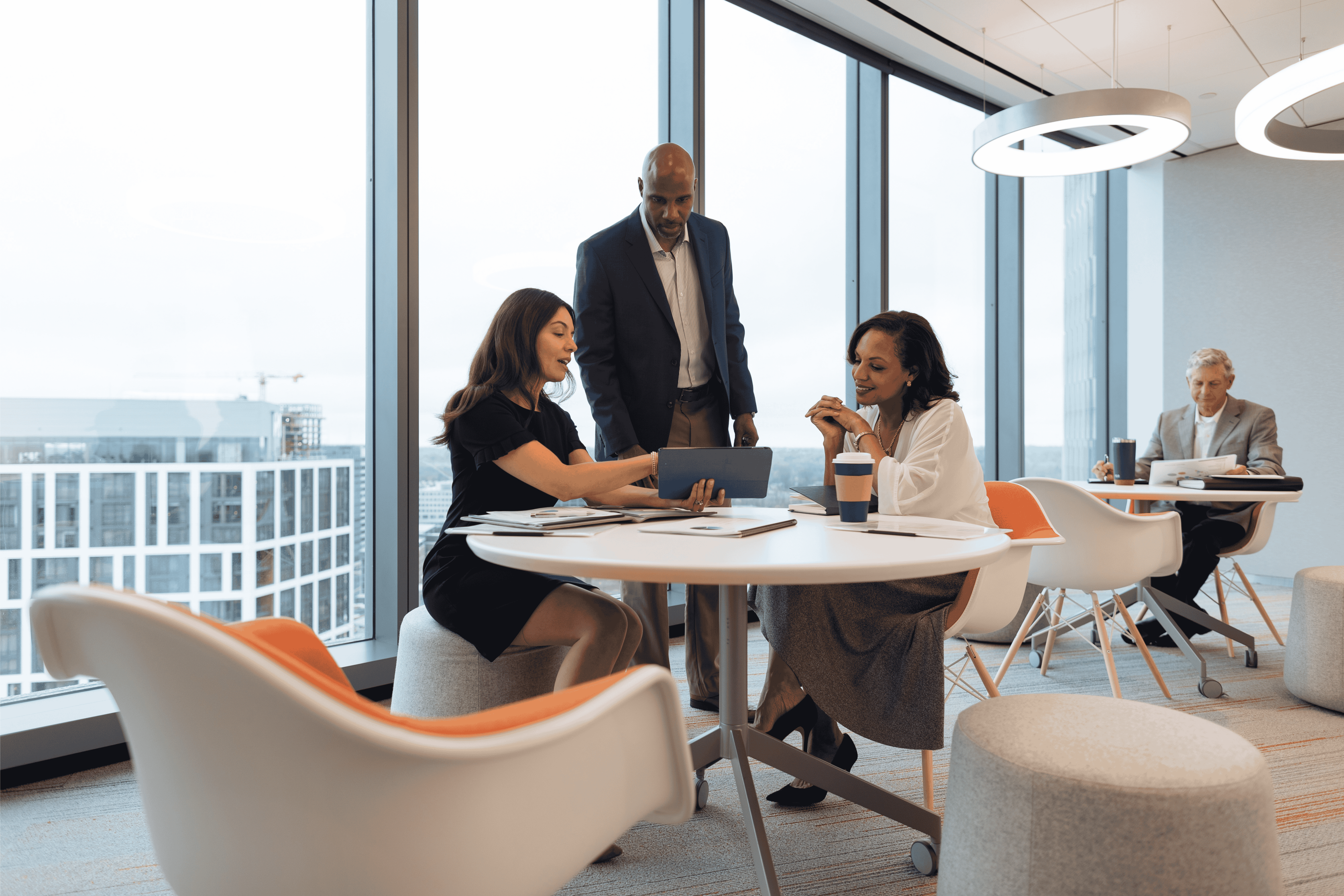 Capital One associates sitting and standing around table pointing at a tablet