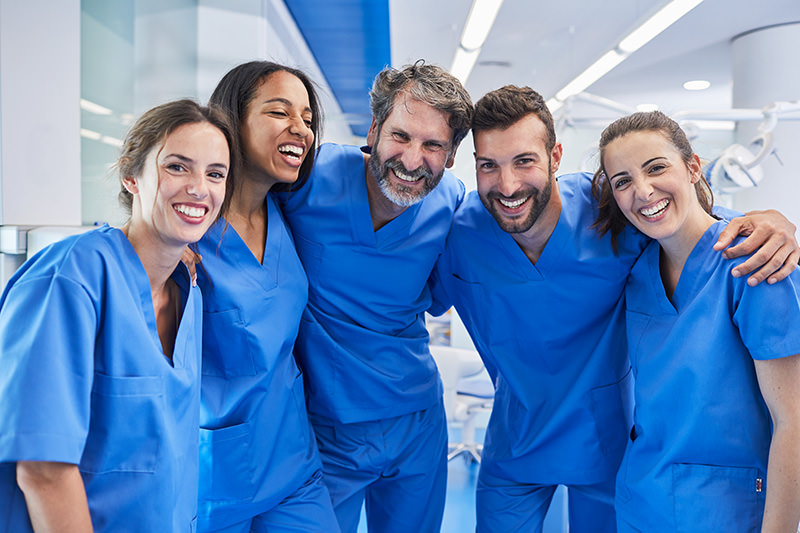 Team wearing blue scrubs smiling at the camera