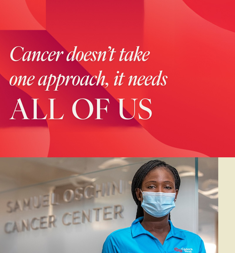 A woman wearing a blue polo shirt with a Cedars-Sinai logo and a surgical mask stands in front of a sign that reads "SAMUEL OSCHIN CANCER CENTER.