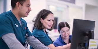 three medical nurses looking at a screen