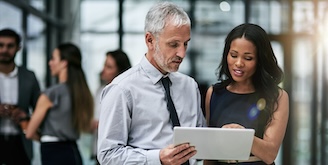 Two professional coworkers using a digital tablet together at work