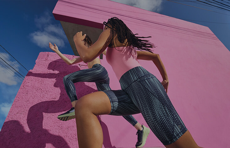 Two women running in front of a bright pink building