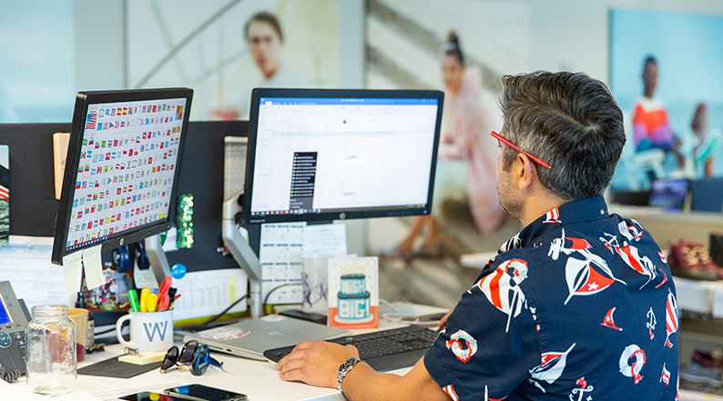 A man with his back to the camera works on his computer