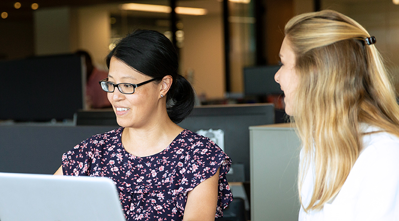 Two women talk at a conference table 