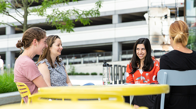 Four women sit outside having a conversation