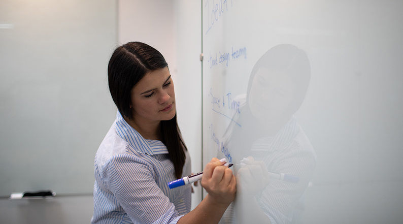 A woman writes on a whiteboard