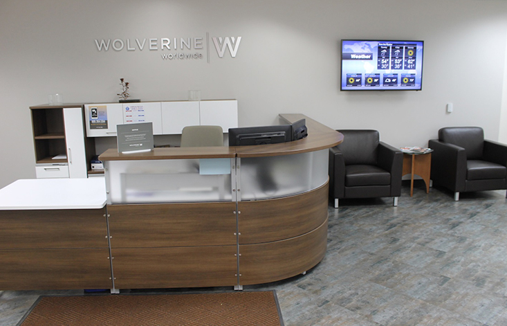 A receptionist’s desk with the Wolverine logo on the wall