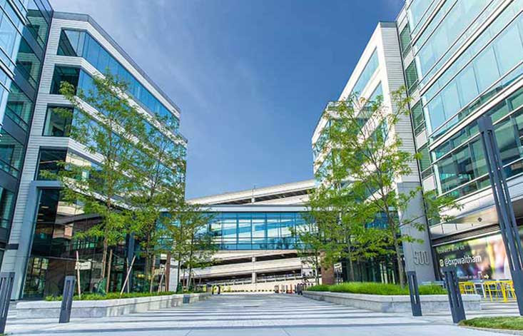 A glass and steel campus with tree-lined walkways